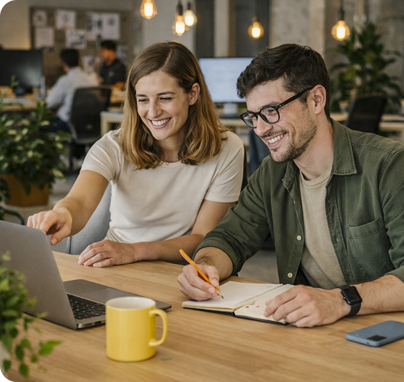 Two colleagues smiling while reviewing feedback together on a laptop